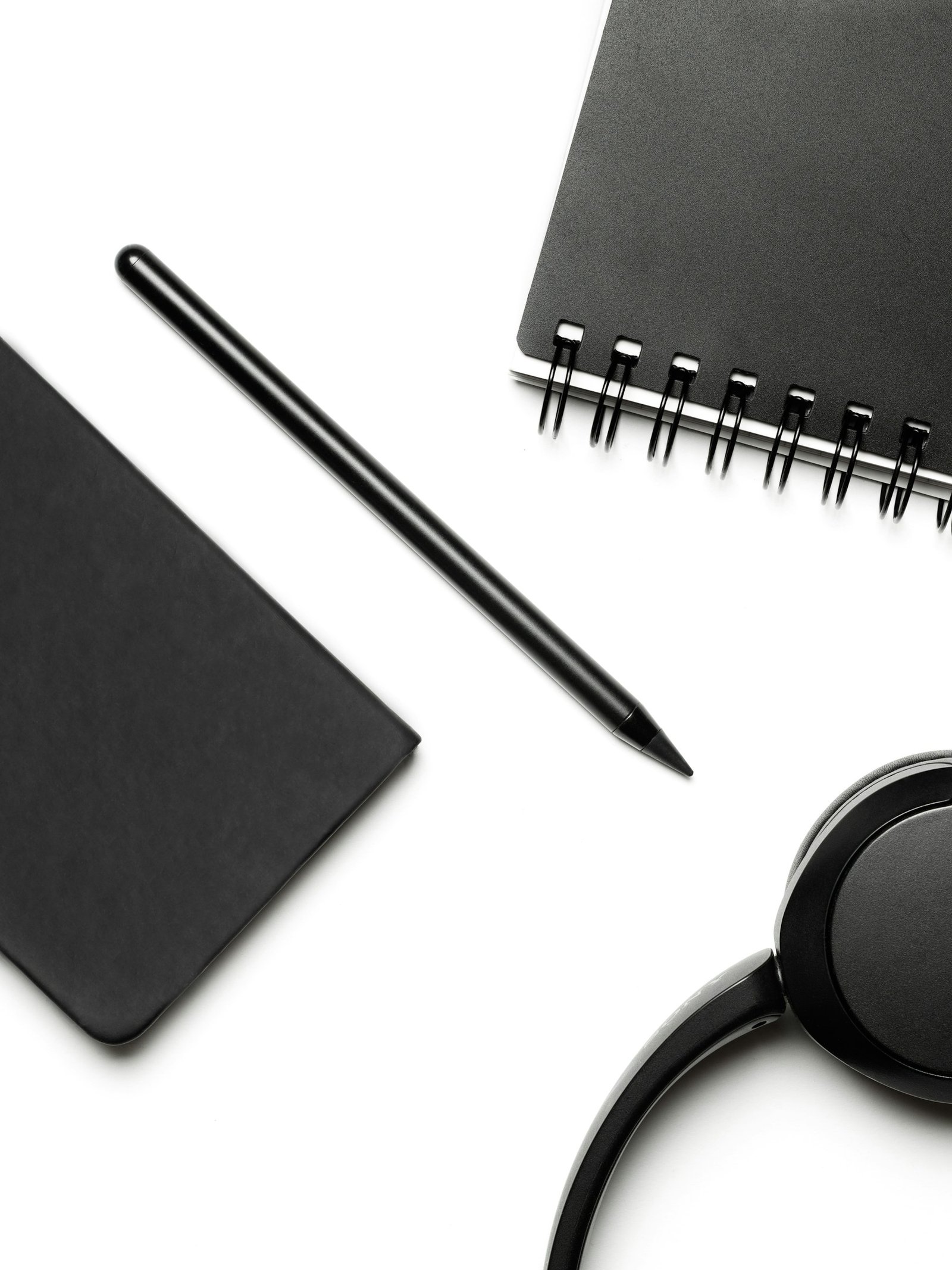 Cuadernos, lápiz y auriculares sobre una mesa de trabajo